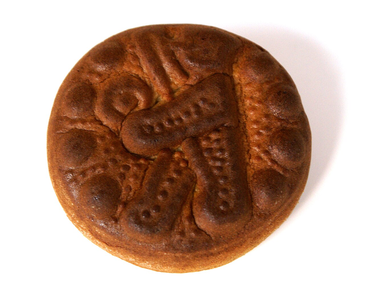 Photographie illustrative : Biberli rond gravé de motifs, photographié sur fond blanc.