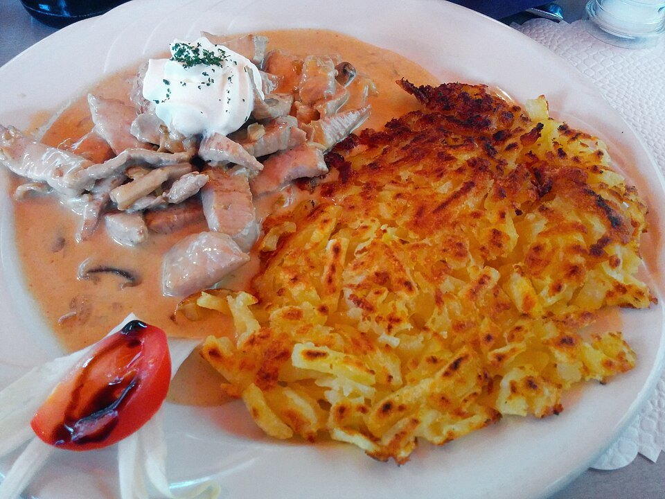 Photographie illustrative : Émincé à la sauce crémeuse, servi avec des rösti dorés.