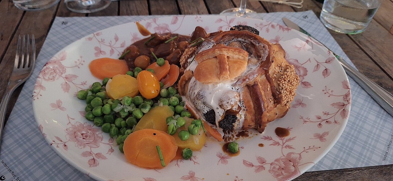 Photographie illustrative : Bouchée en pâte feuilletée garnie, servie avec des légumes.